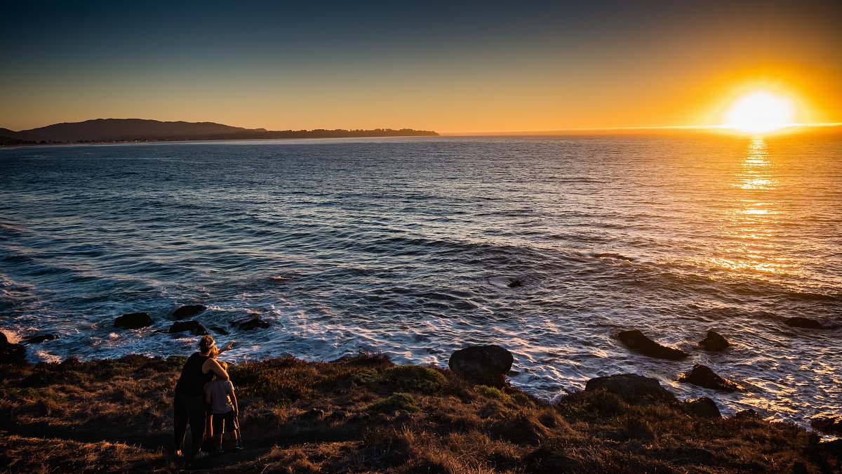 human woman and children standing in front of sea during sunset person
