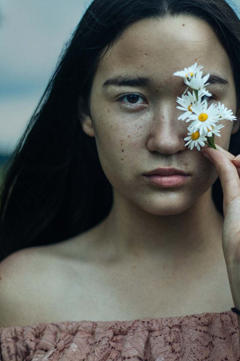 human woman covering her eyes with white flowers person