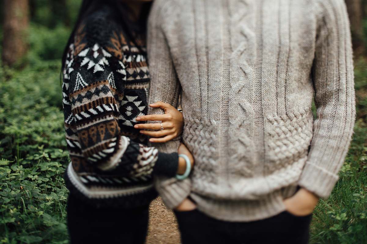 person woman in black and white sweater hugging man in gray cable knit sweater sweater