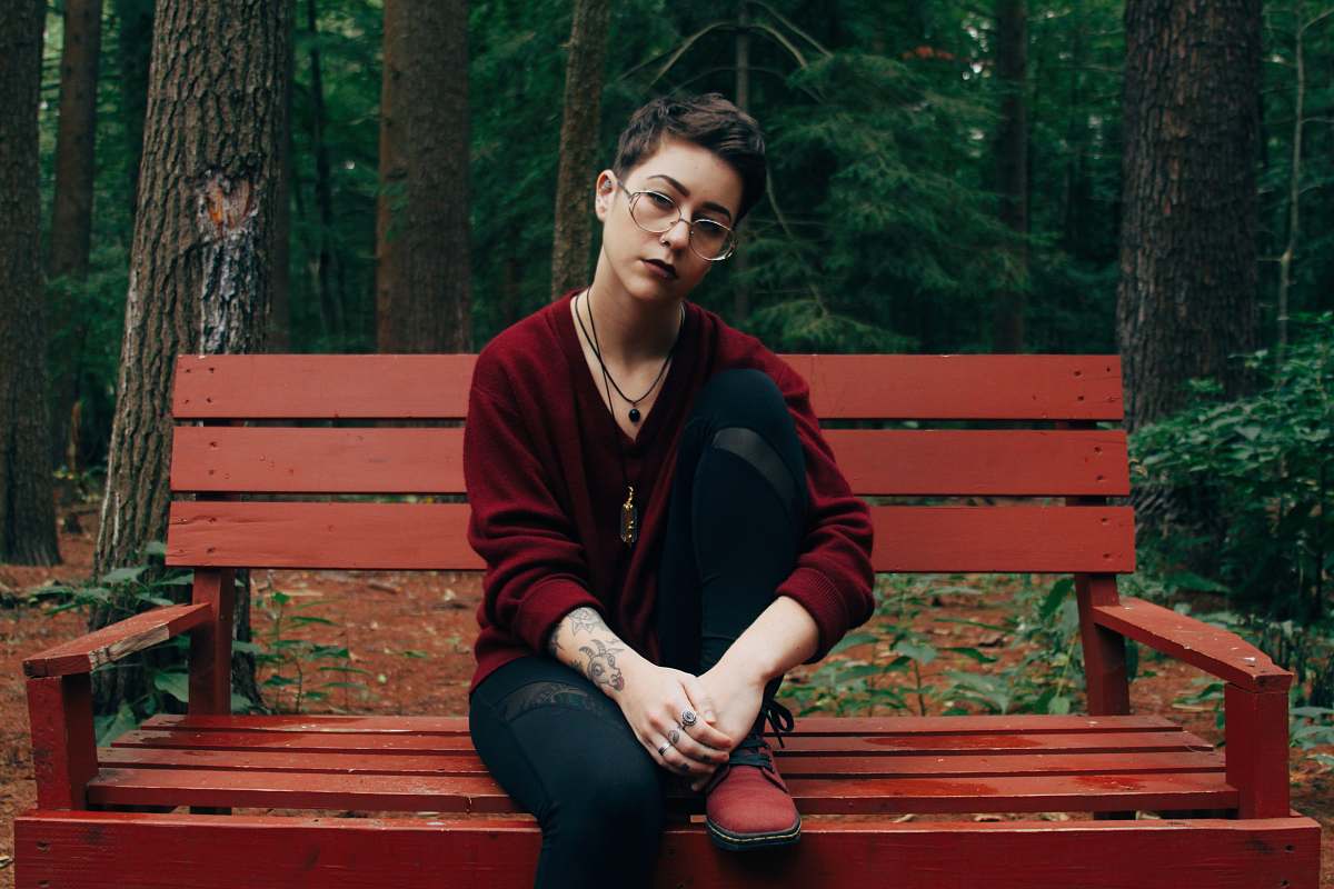 human woman sitting on bench near forest person