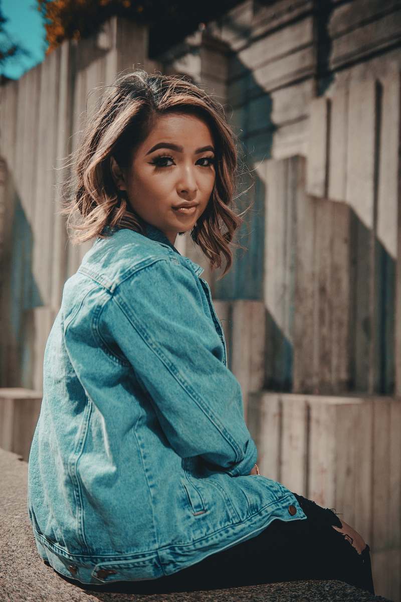 human woman sitting on fence facing to the camera during dayime woman