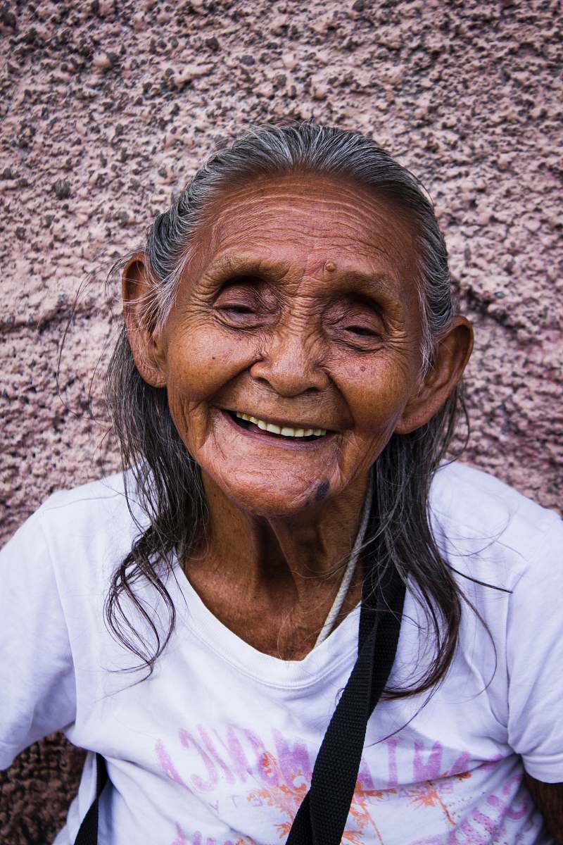 human woman smiling while leaning on gray wall person
