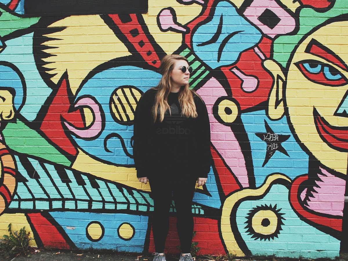 human woman standing beside wall with graffiti person