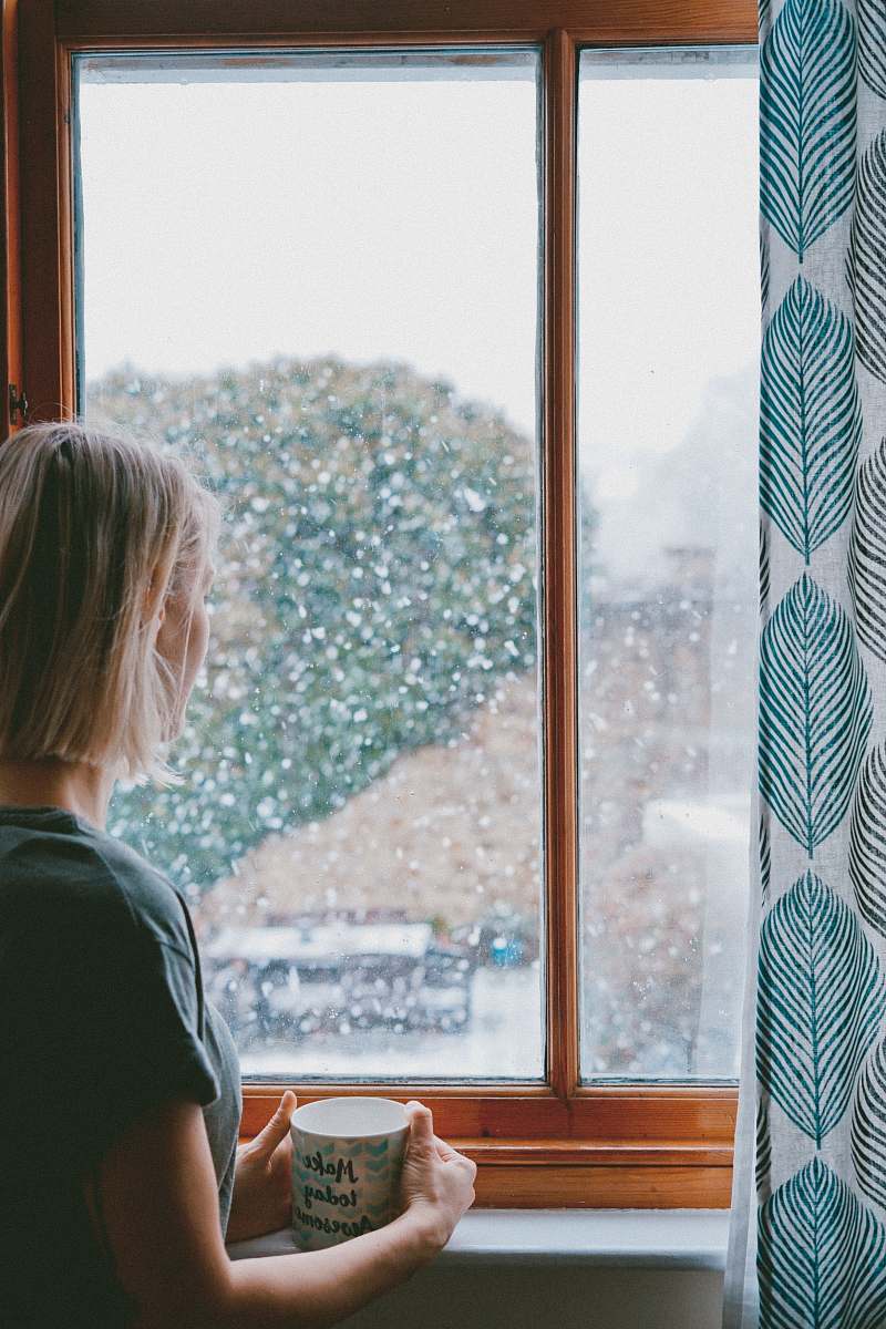 human woman standing in front of clear glass window cup