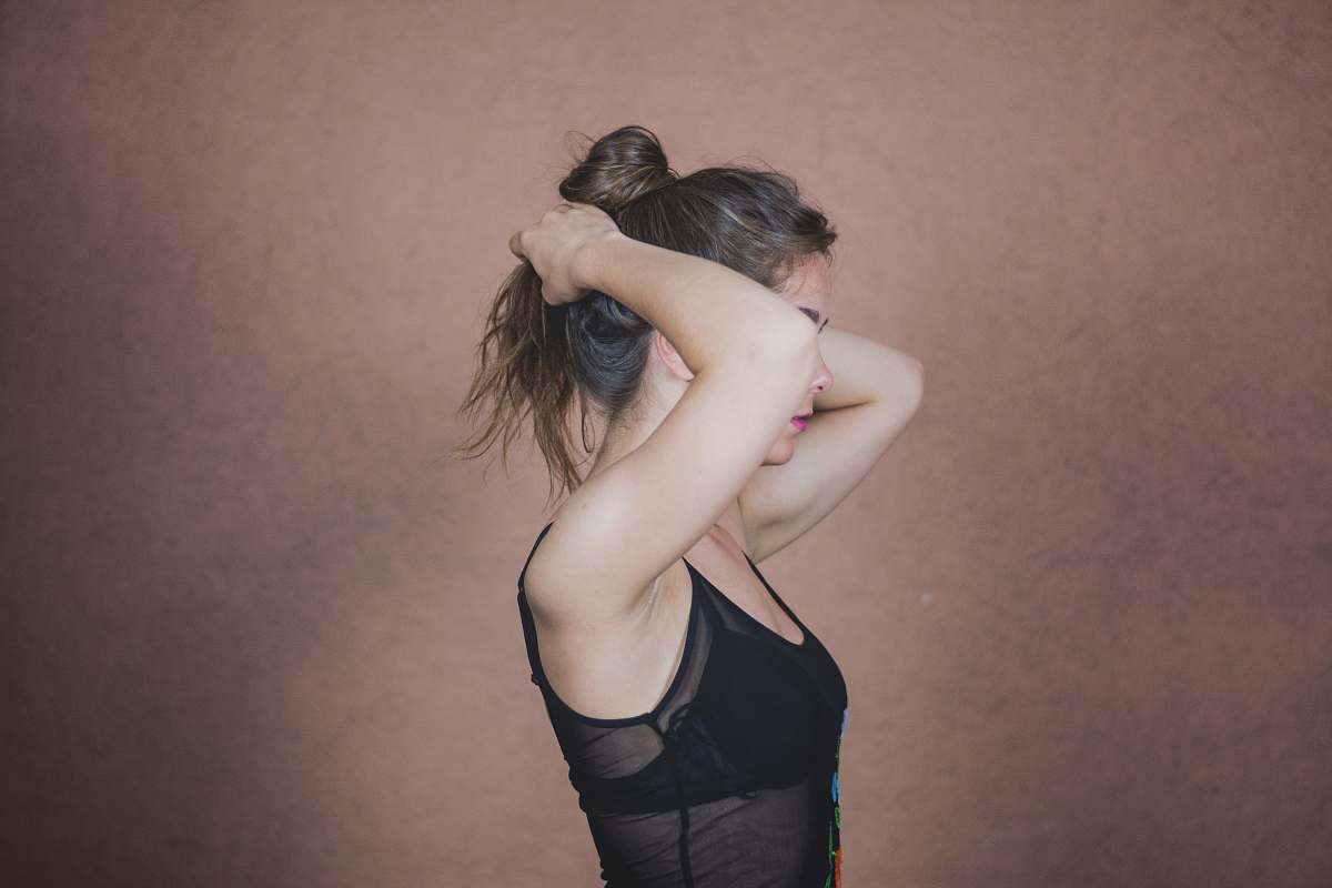 human woman standing in front of concrete wall facing sideways hair