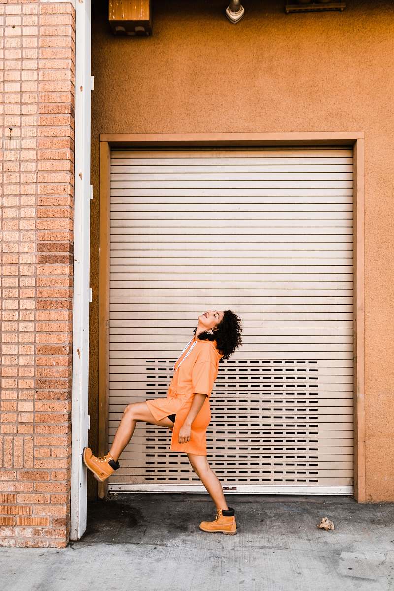 human woman stepping her right foot on wall near roller shutter person