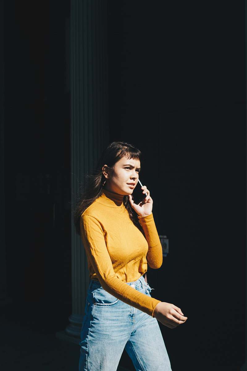 person woman walking with phone on her right ear during daytime human