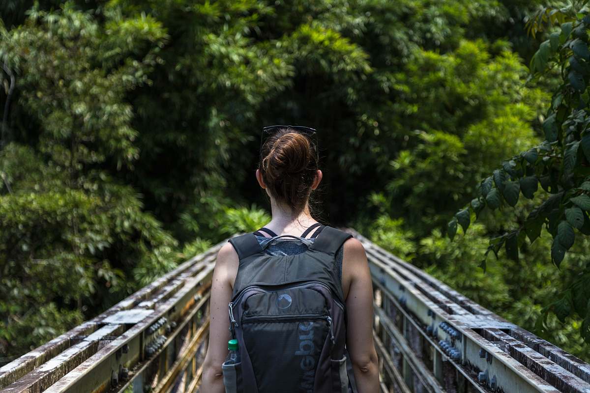 person woman wearing backpack walking on bridge human
