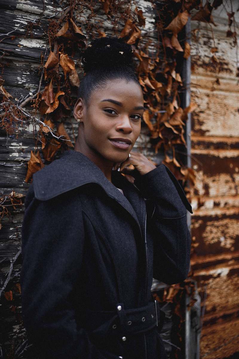 person woman wearing black coat standing near dried leaves human