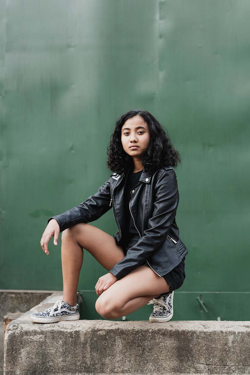 human woman wearing black zip-up jacket and short shorts in sitting position during daytime person