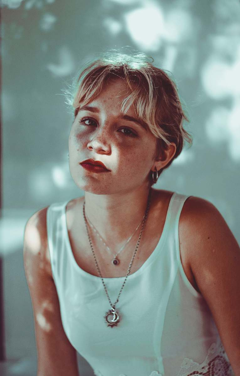 human woman wearing white top near white painted wall person