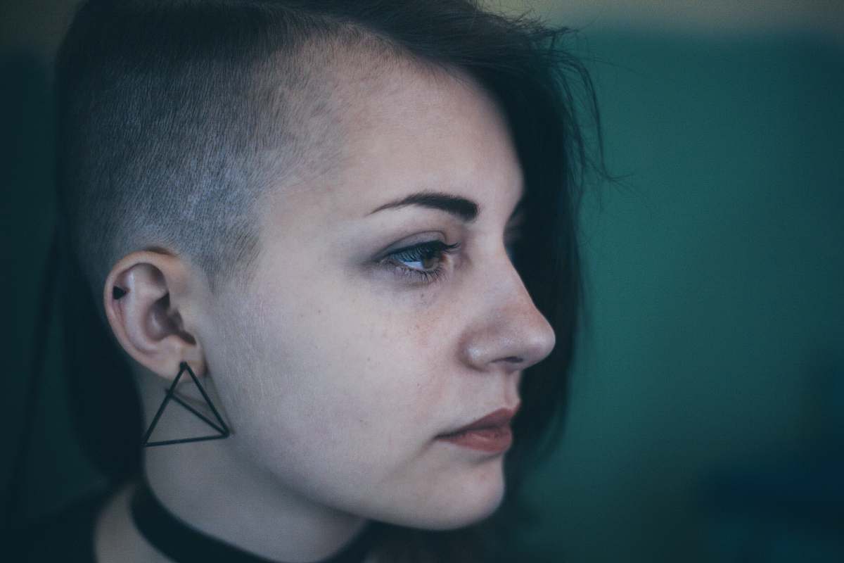 person Woman with an edgy shaved haircut looks sad and defeated human