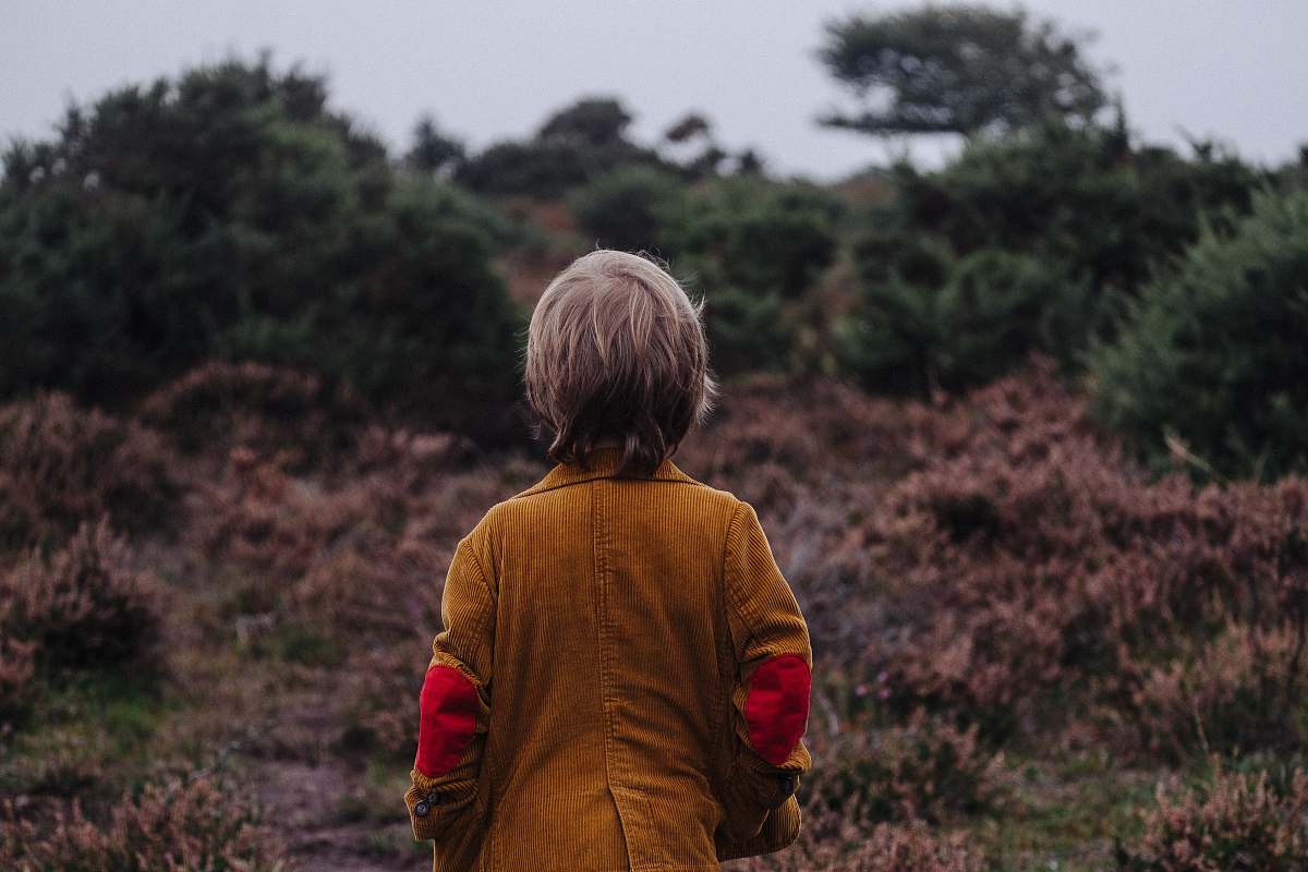 people boy wearing brown coat looking on trees in shallow focus photography human
