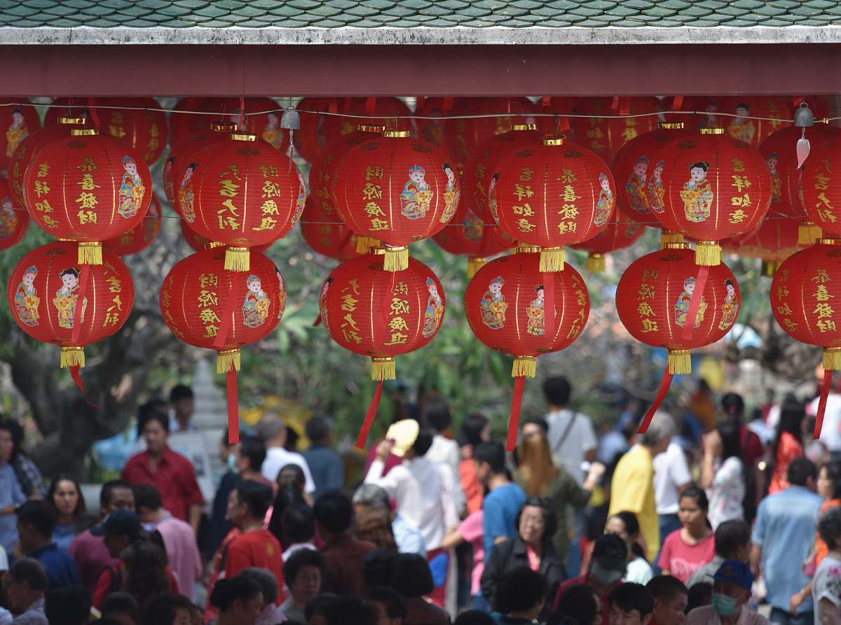 people hanging round red lanterns near crowd at daytime lantern