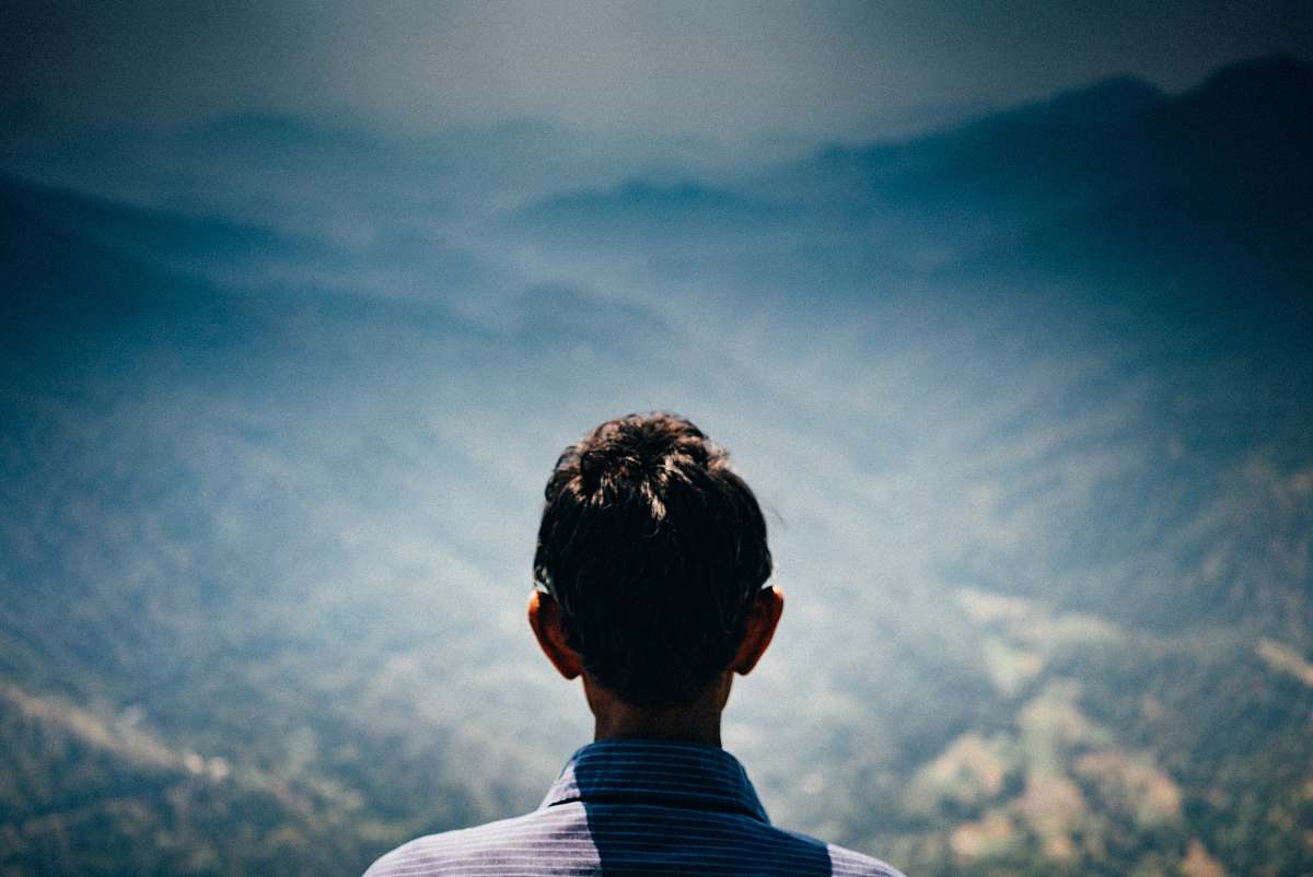 people man facing green mountains during daytime human