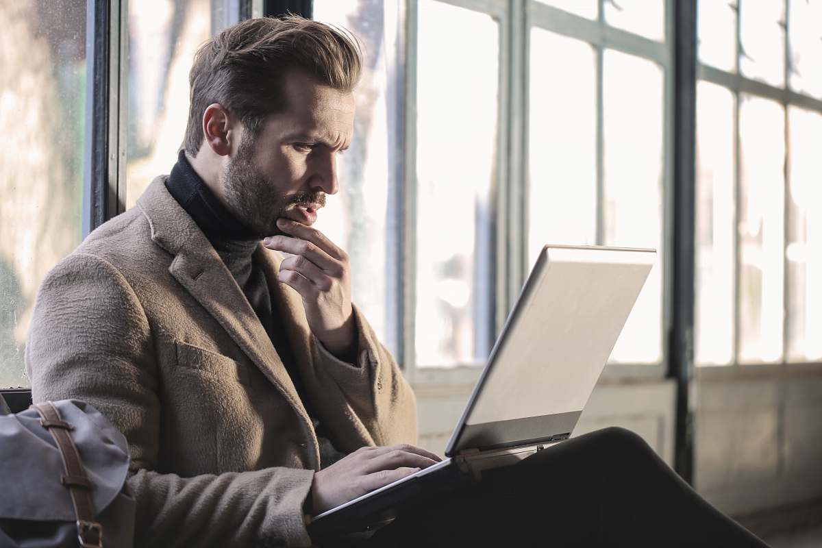 people man holding his chin facing laptop computer computer