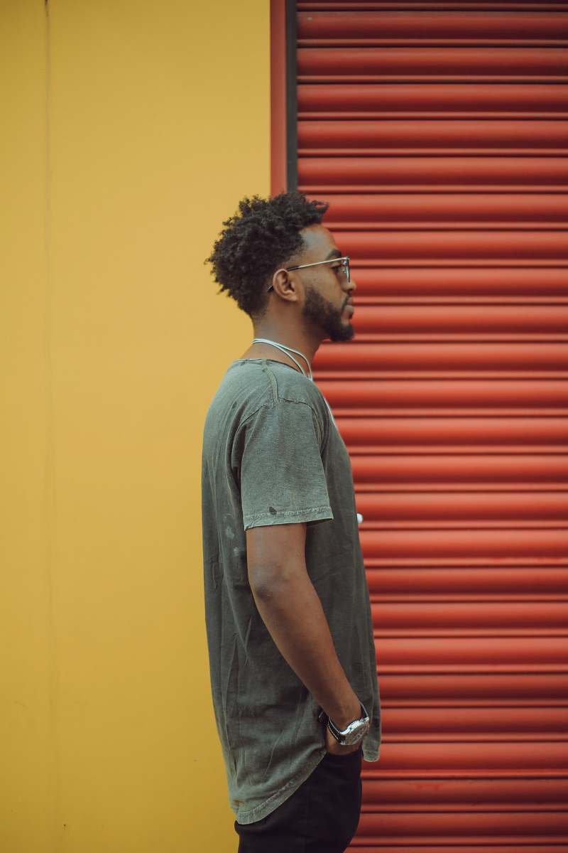 people man in gray t-shirt standing near red roll up door human