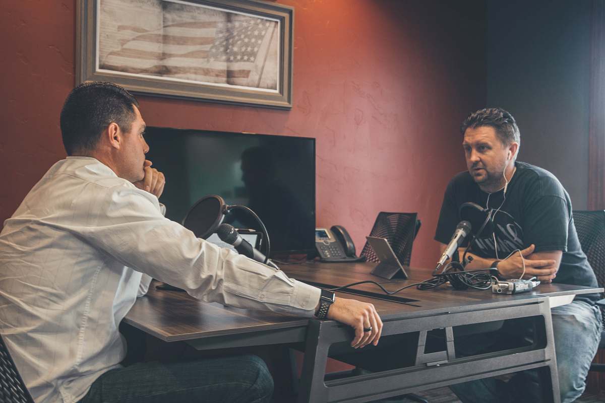 people man sitting in front of another man also sitting inside room human