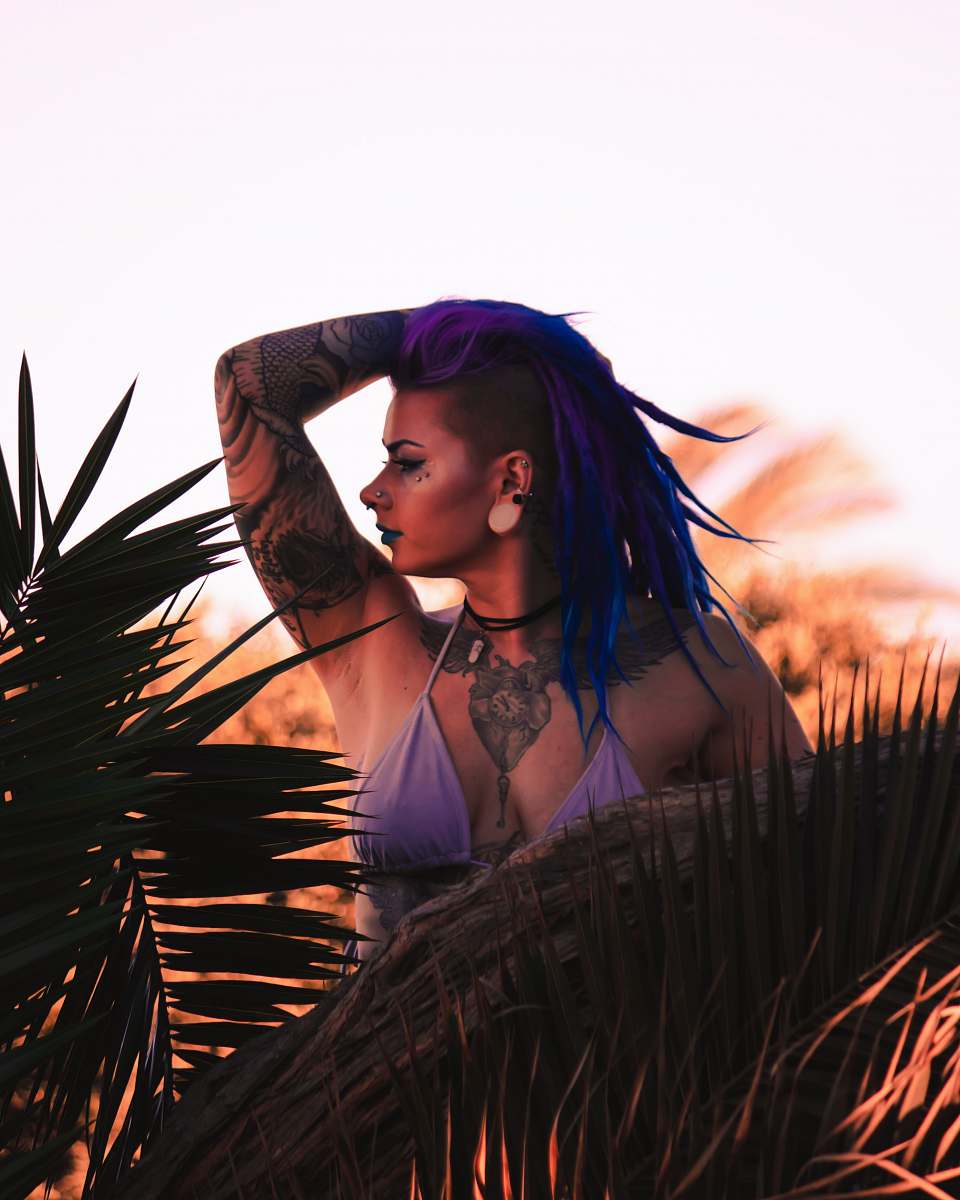 human woman in purple bikini top standing near plant while holding her head people