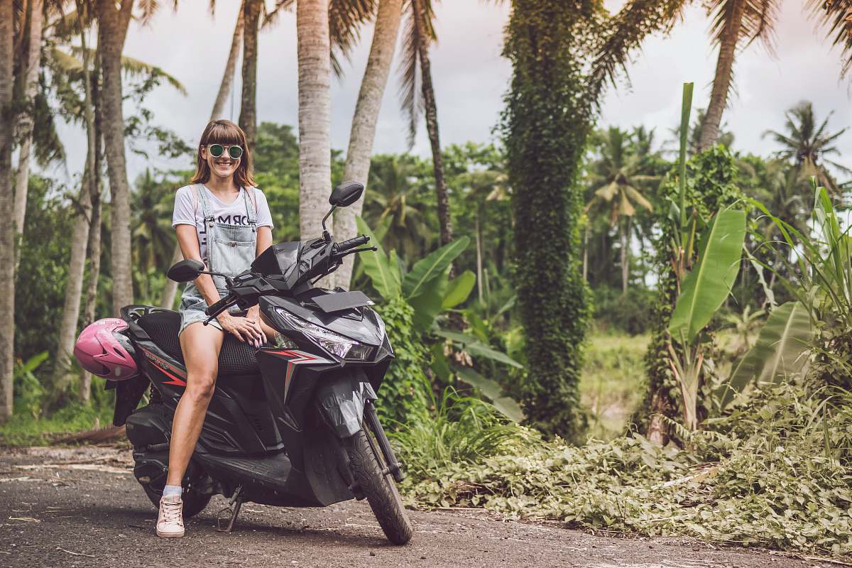 people woman smiling on top of black motor scooter human