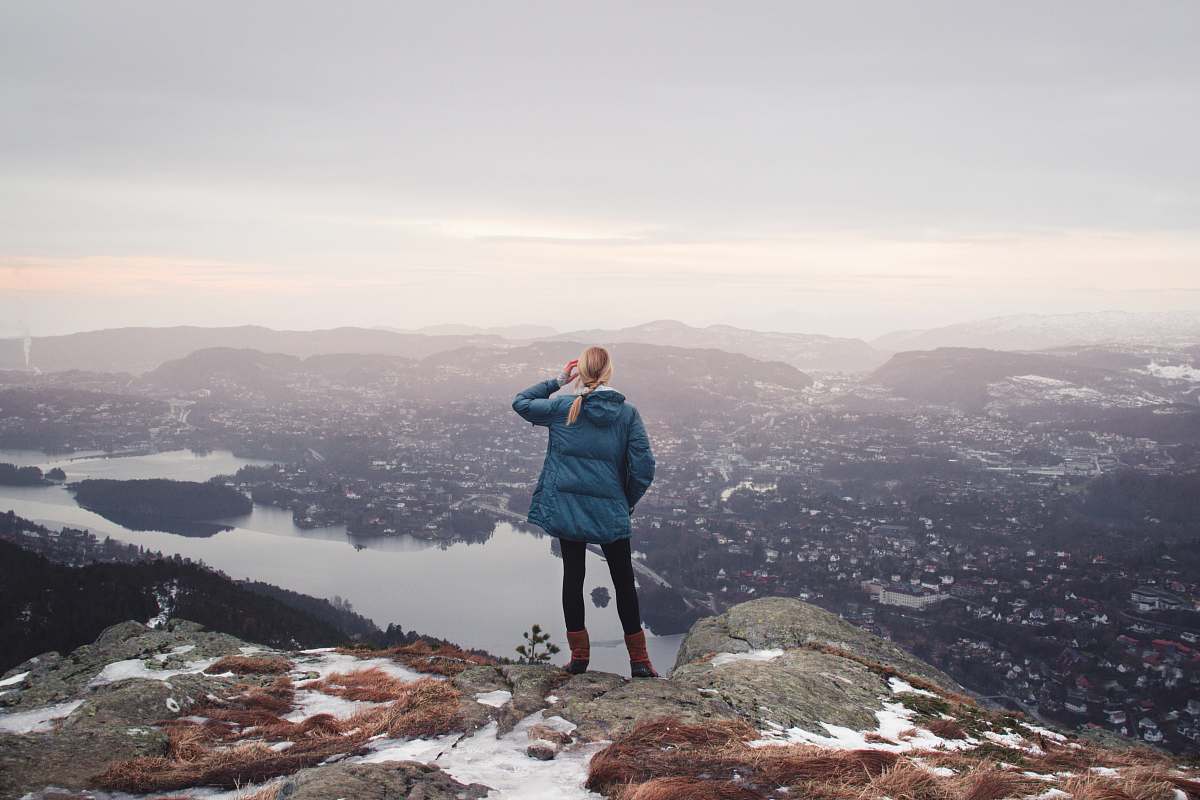 people woman standing on cliff near body of water during daytime human