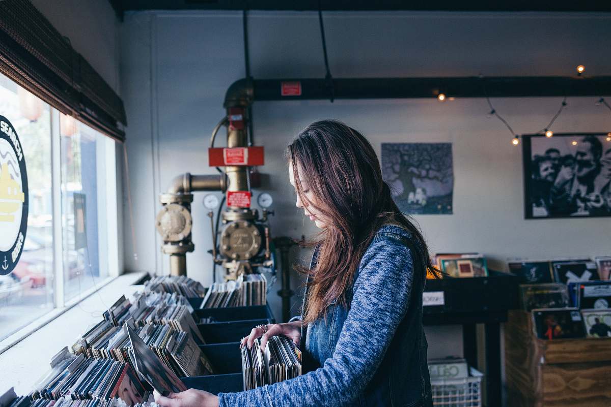 people woman standing on stereo sleeve rack holding a sleeve facing glass window during daytime human