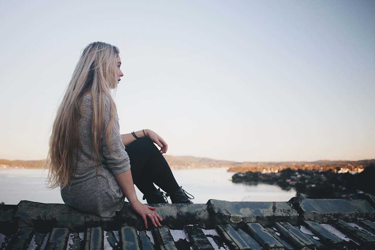 female woman sitting on gray dock near bpdy of water girl