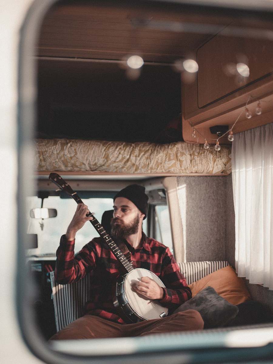 human man sitting inside vehicle while playing mandoline person