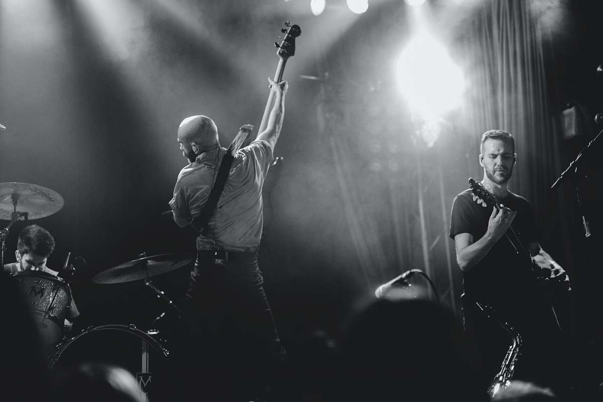 person grayscale photo of band playing on stage people