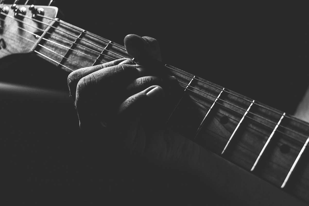 grey grayscale photo of person holding guitar neck and strings guitar