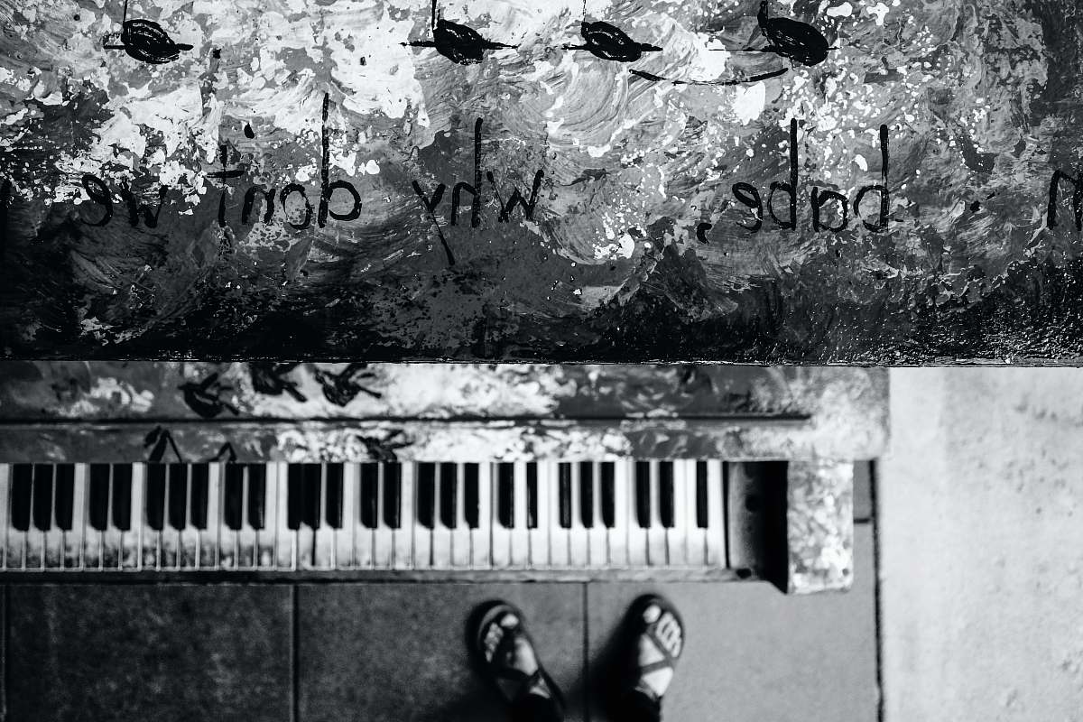 animal grayscale photo of person standing near piano bird
