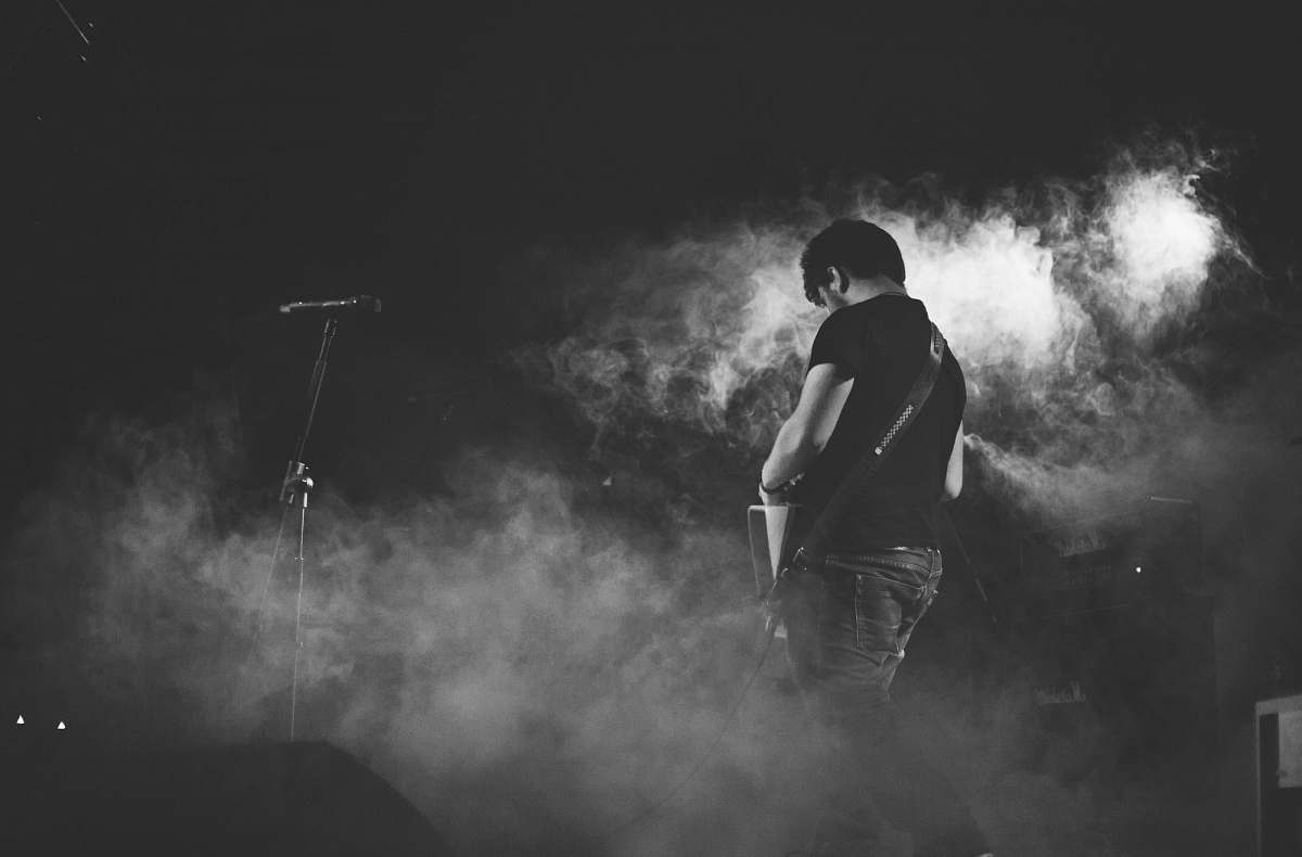 grey grayscale photography of man performing guitar on stage person