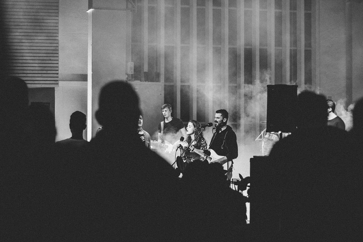 grey man standing while singing on stage op doortocht