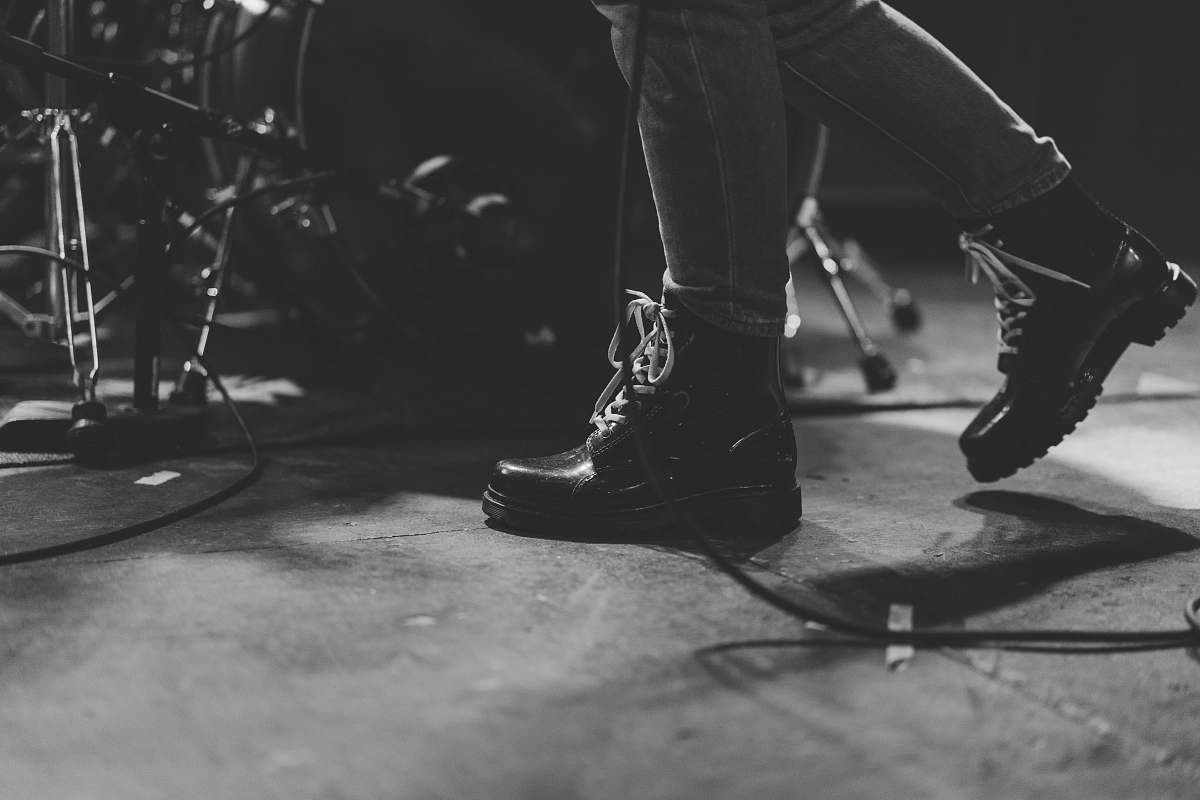 footwear person in black leather boots walking beside of drum set clothing