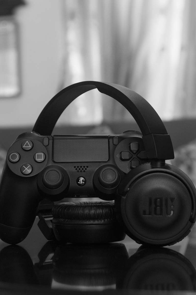 grey Sony PS DualShock 4 beside JBL wireless headphones camera