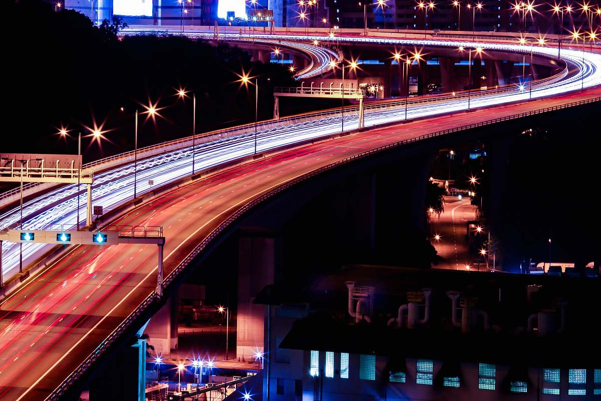 building time lapse photography of road with cars near building at night stage