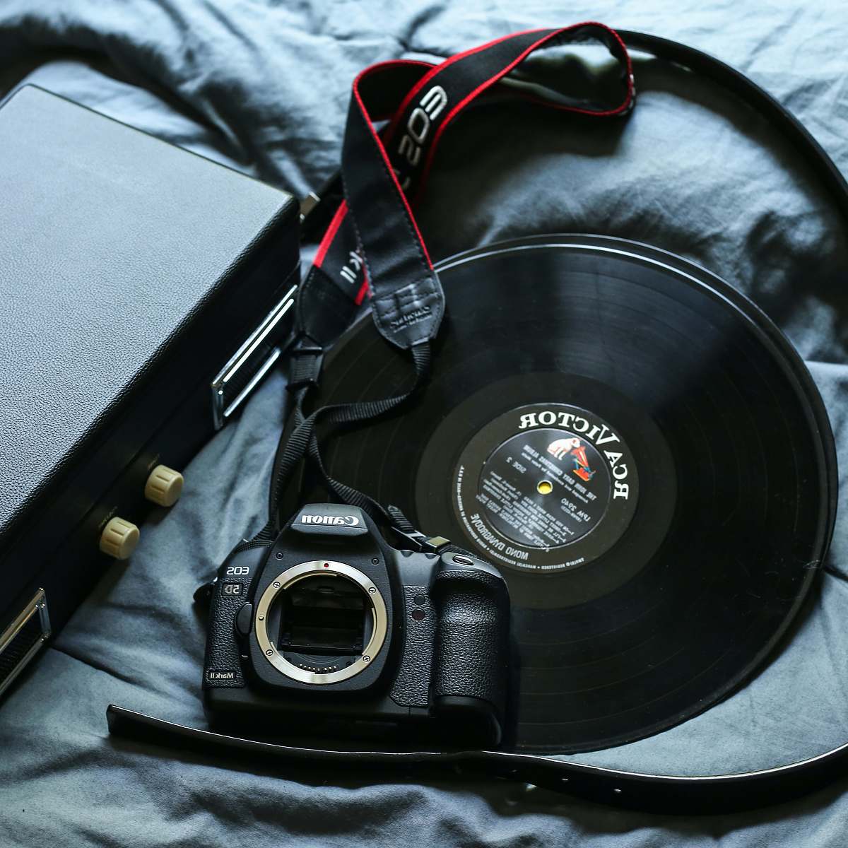 electronics black Canon EOS 5D DSLR camera beside black RCA Victor vinyl record lifestyle