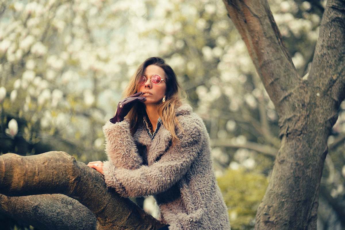 apparel woman in gray coat sitting on tree stem sweater