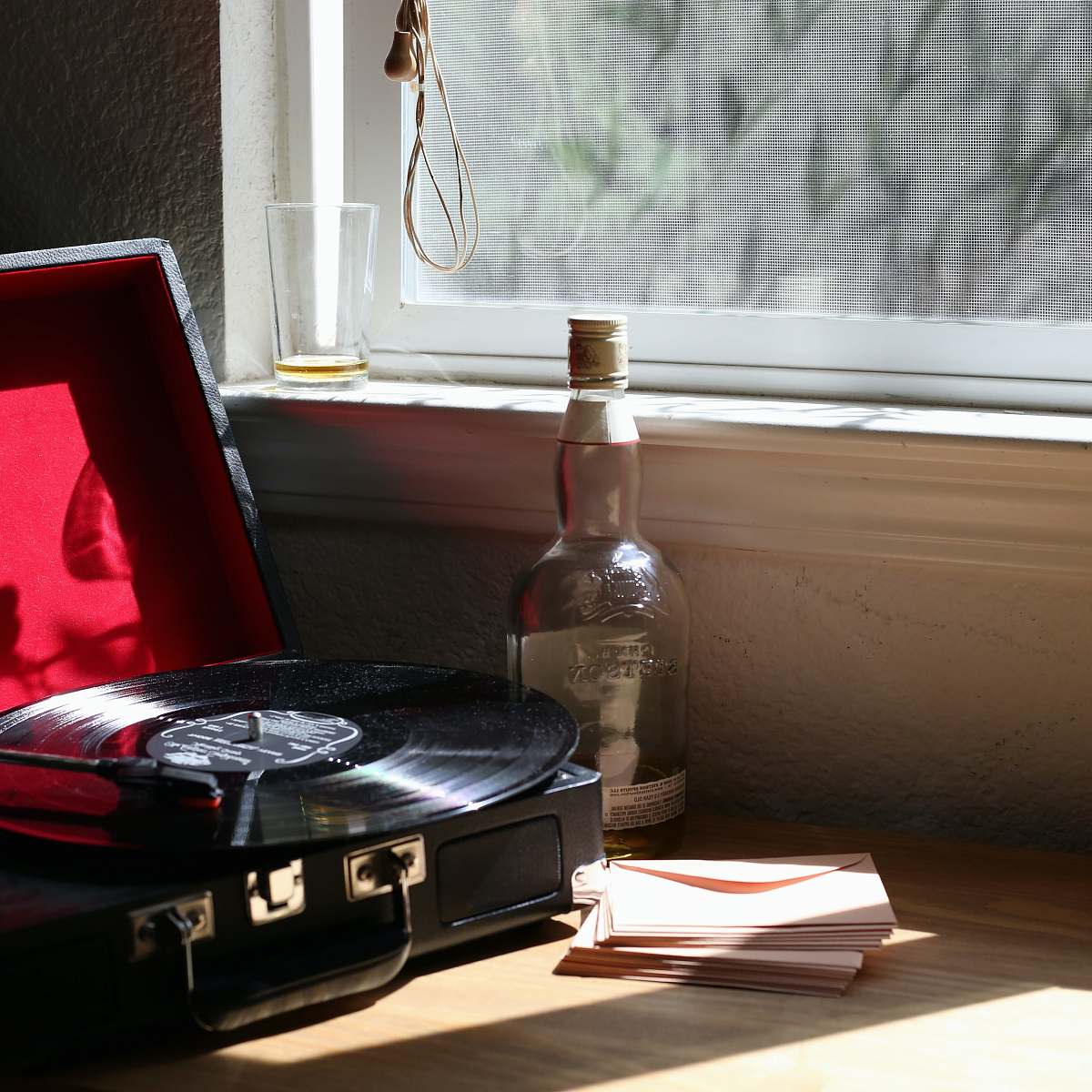 machine black and gray stereo turntable beside clear-glass bottle spoke