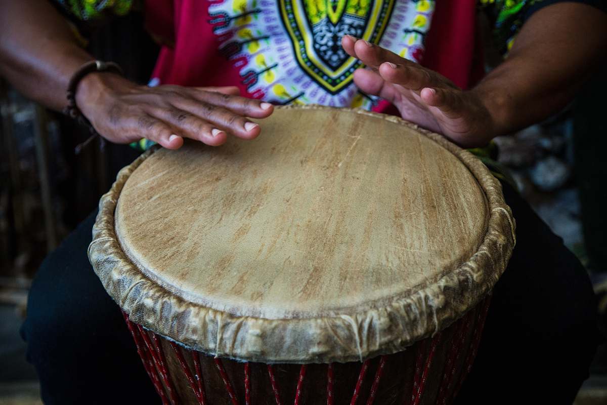 percussion person thumping the round brown and beige drum musical instrument