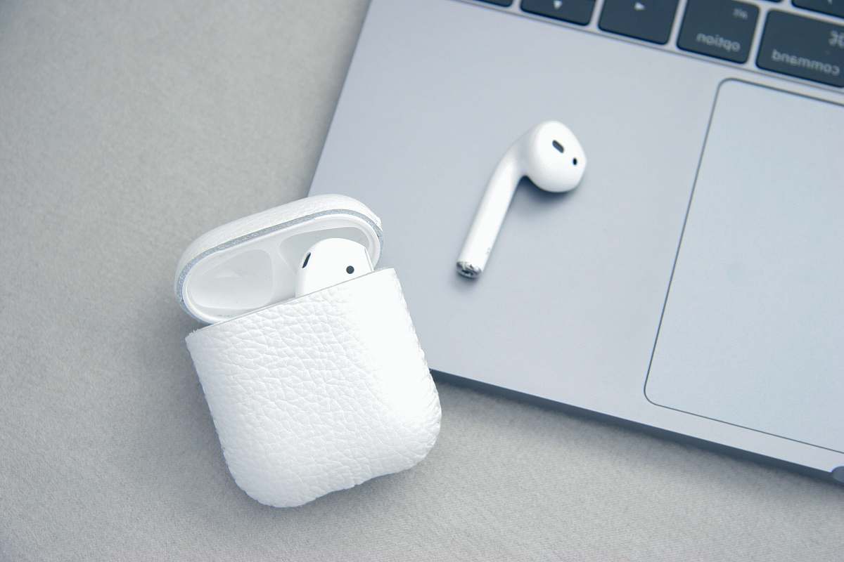 macbook white Apple AirPods beside MacBook Pro earphone