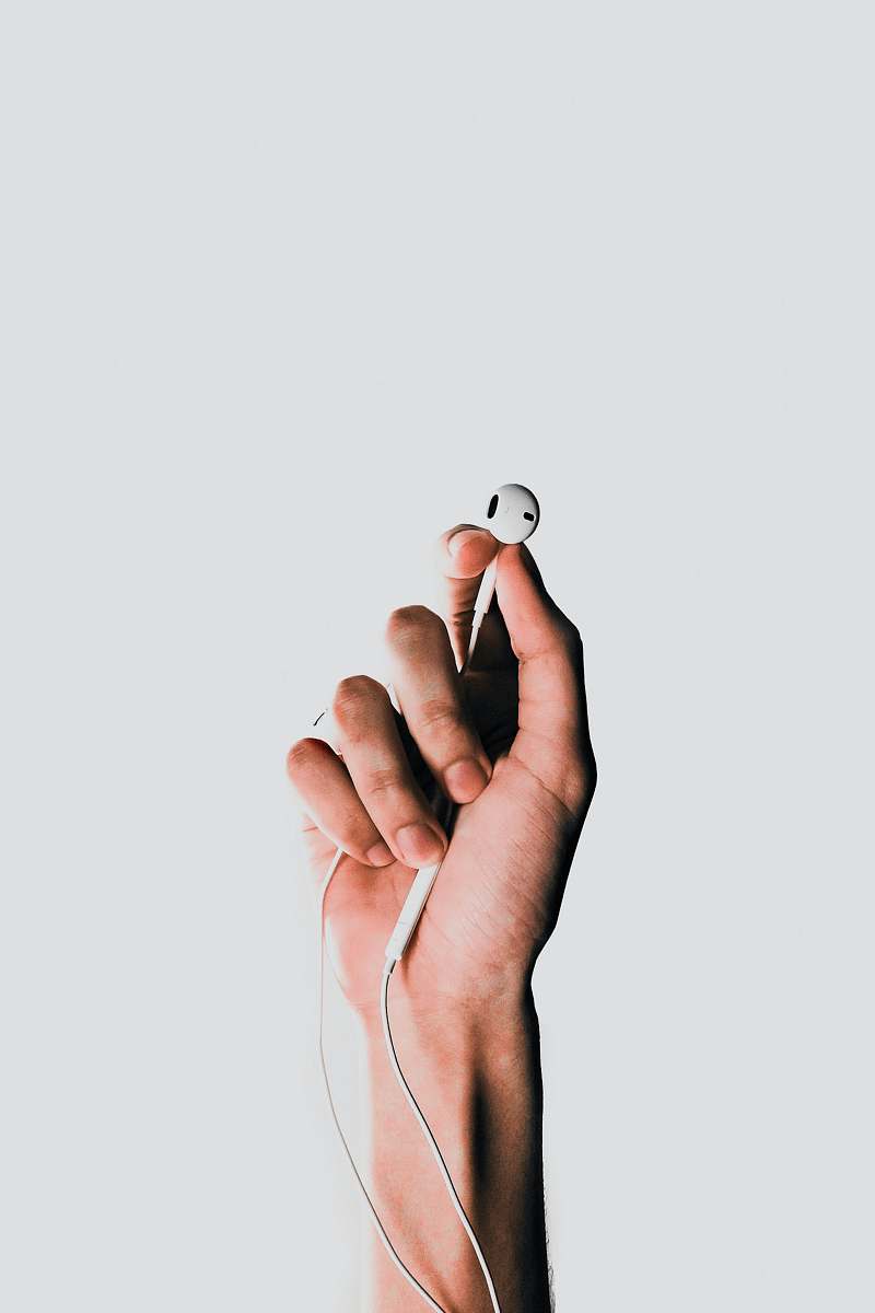 apple person holding Apple EarPods headphone