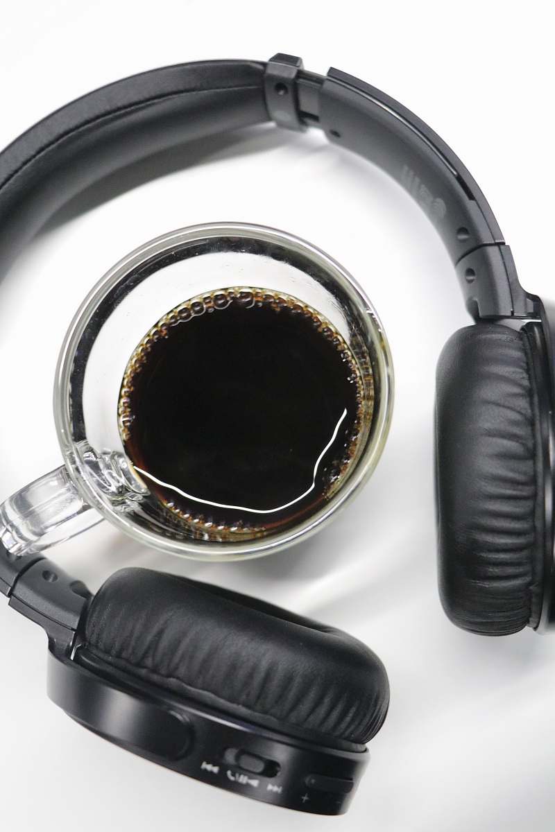headphones half-filled clear glass cup in black wireless headphones headset