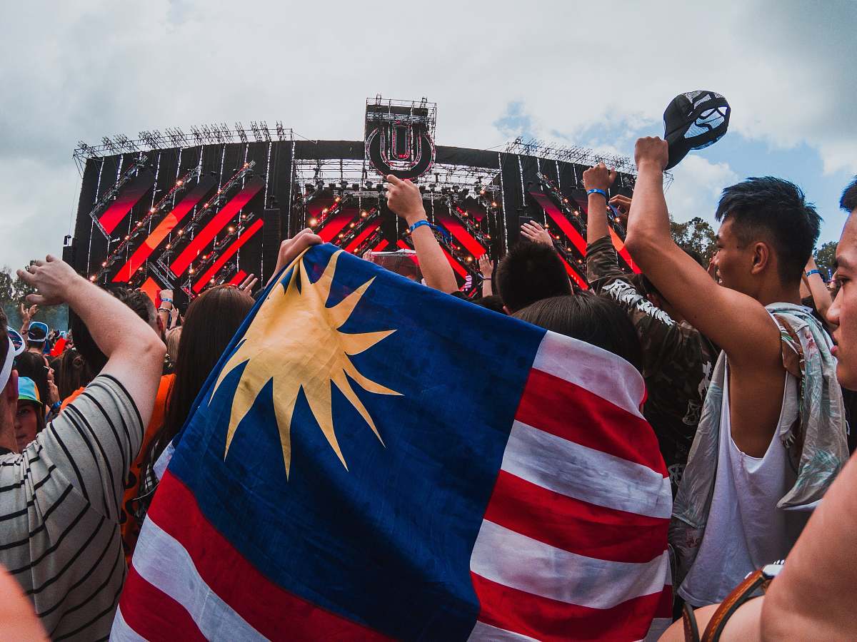 human person holding US flag at crowd under cloudy sky during daytime person