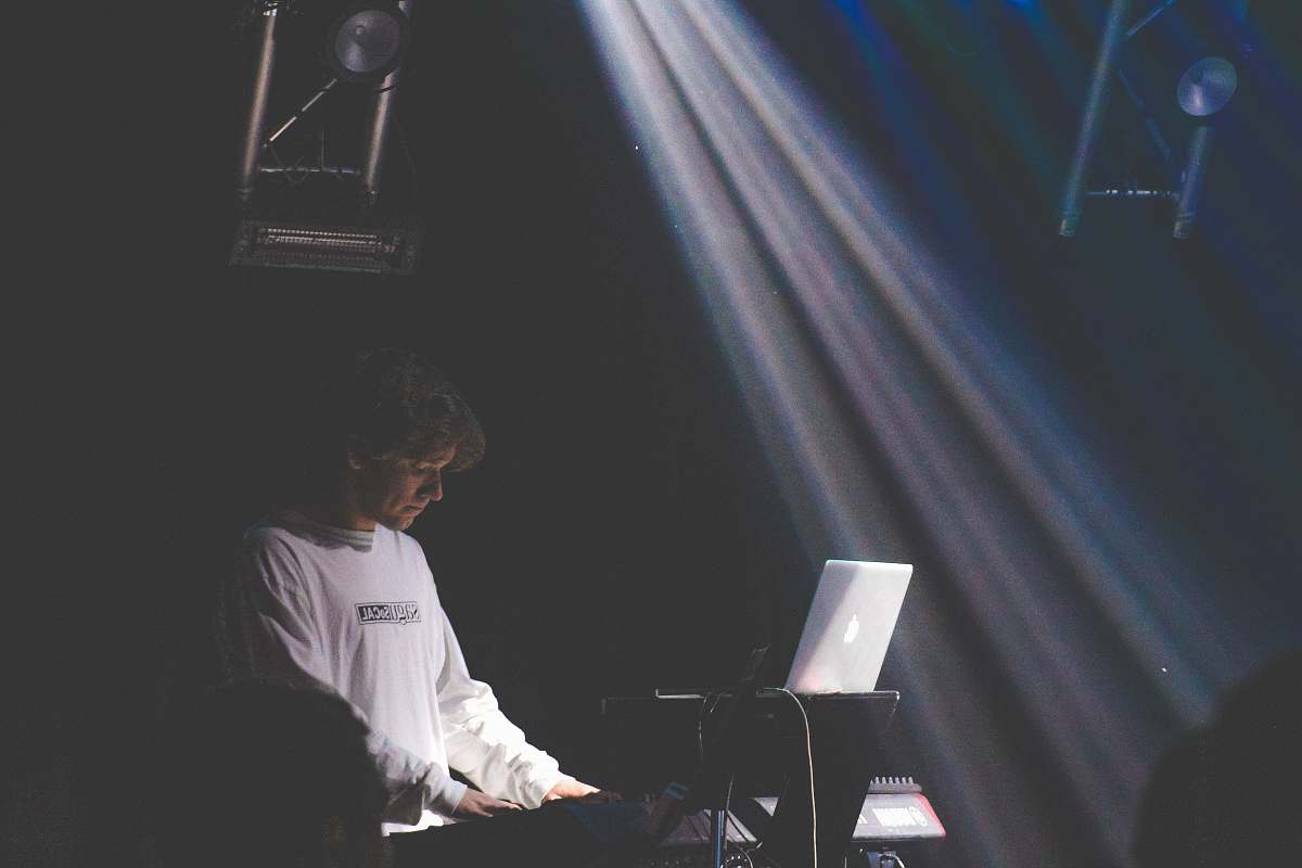 human man in white sweater playing electronic keyboard person