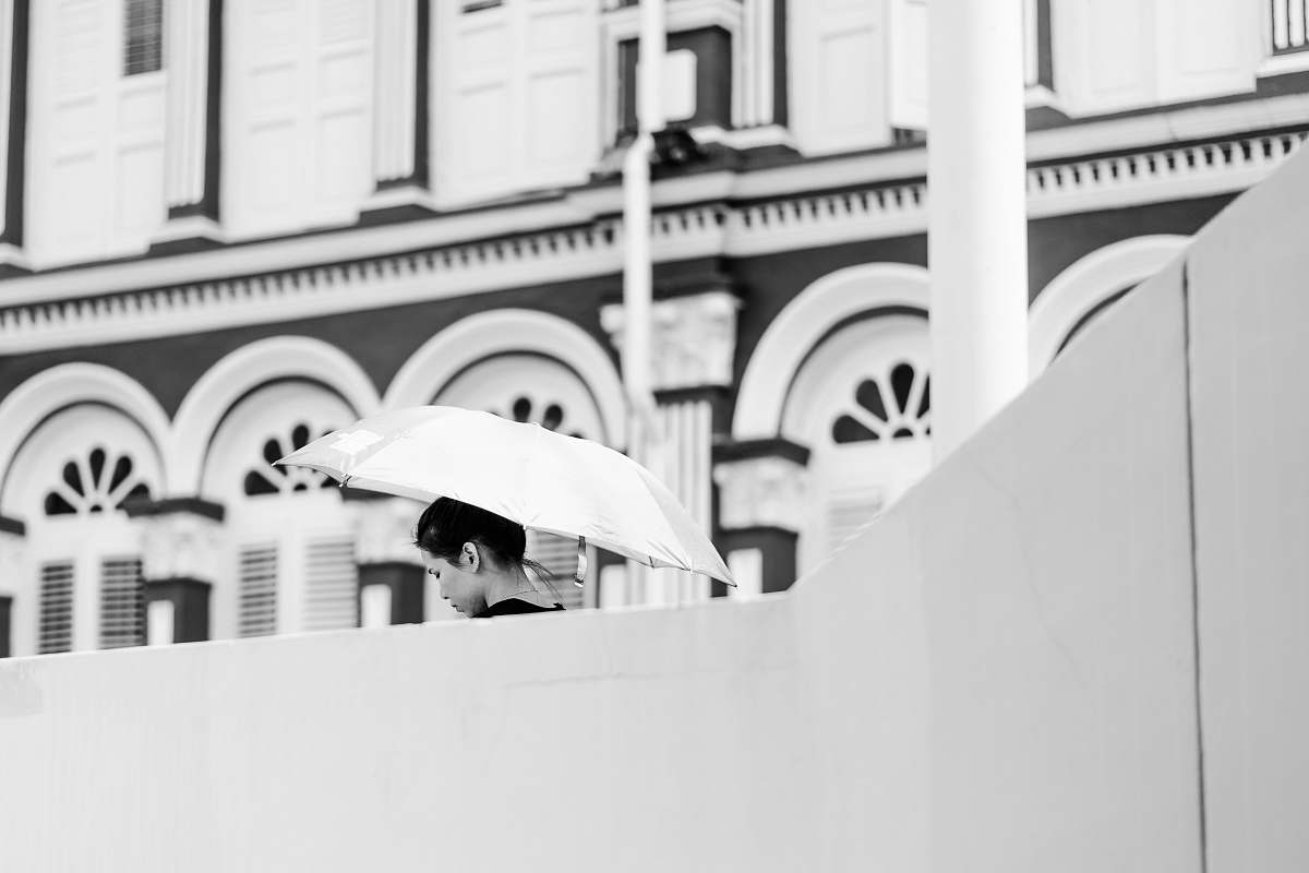 black-and-white woman holding umbrella beside white concrete building leisure activities
