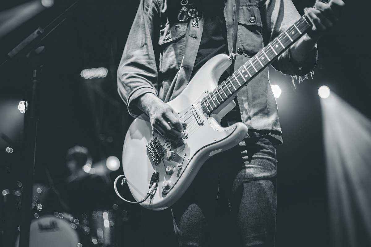 grey man playing electric guitar guitarist