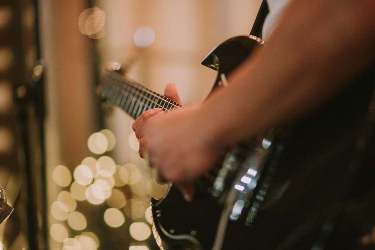 bokeh person playing black SG guitar hands