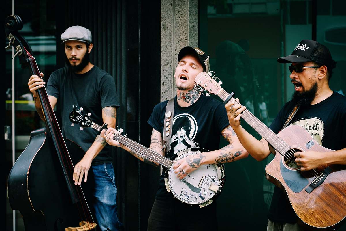 music three men playing stringed instruments during daytime musician
