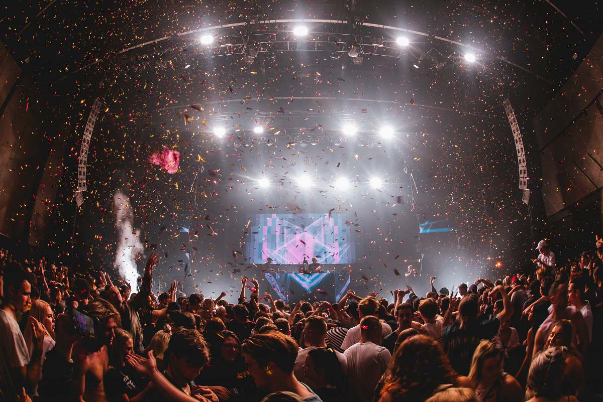 person confetti falling from above at music performance with huge crowd crowd